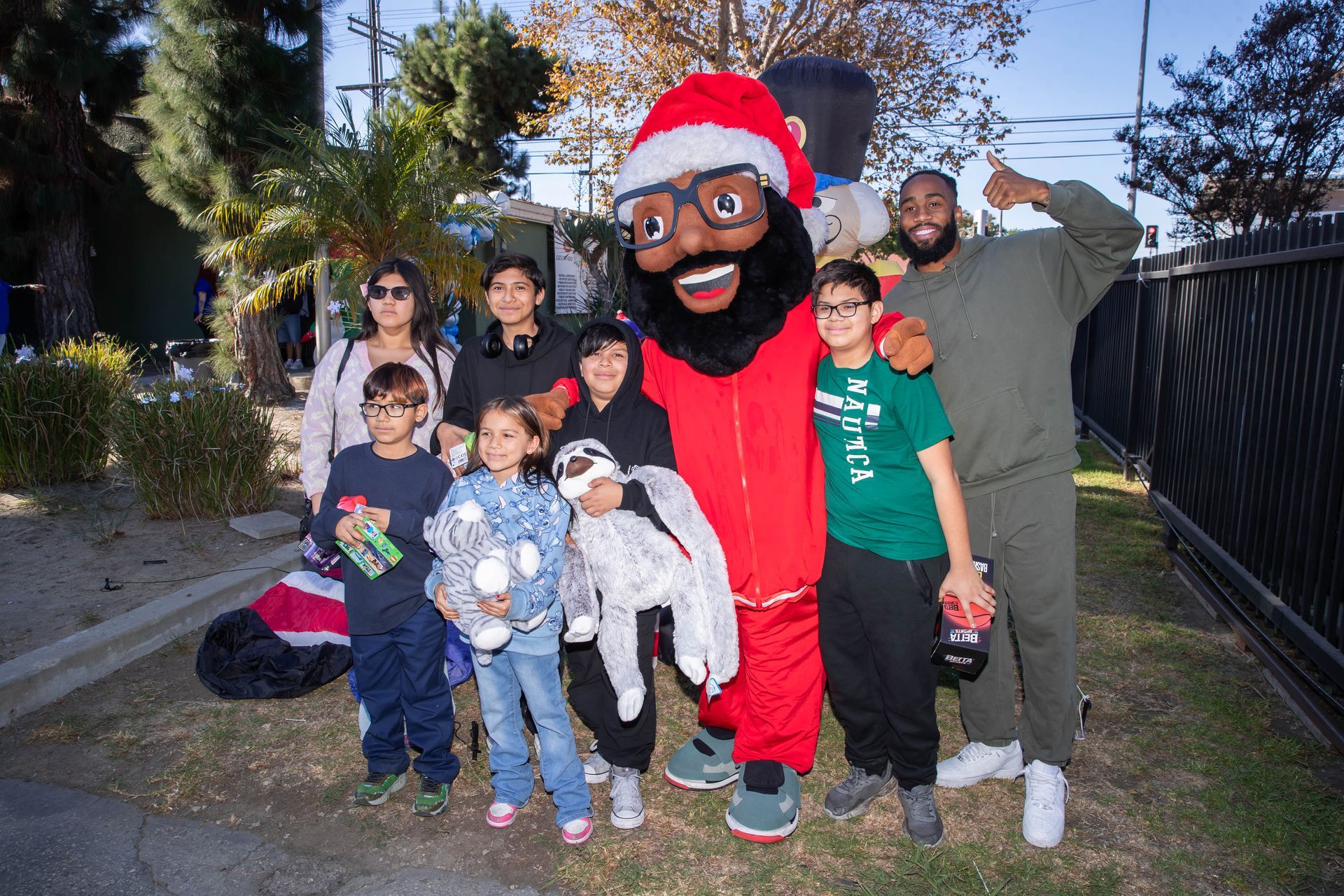 Group poses with Santa-like mascot in outdoor setting; John Johnson III gives thumbs up.