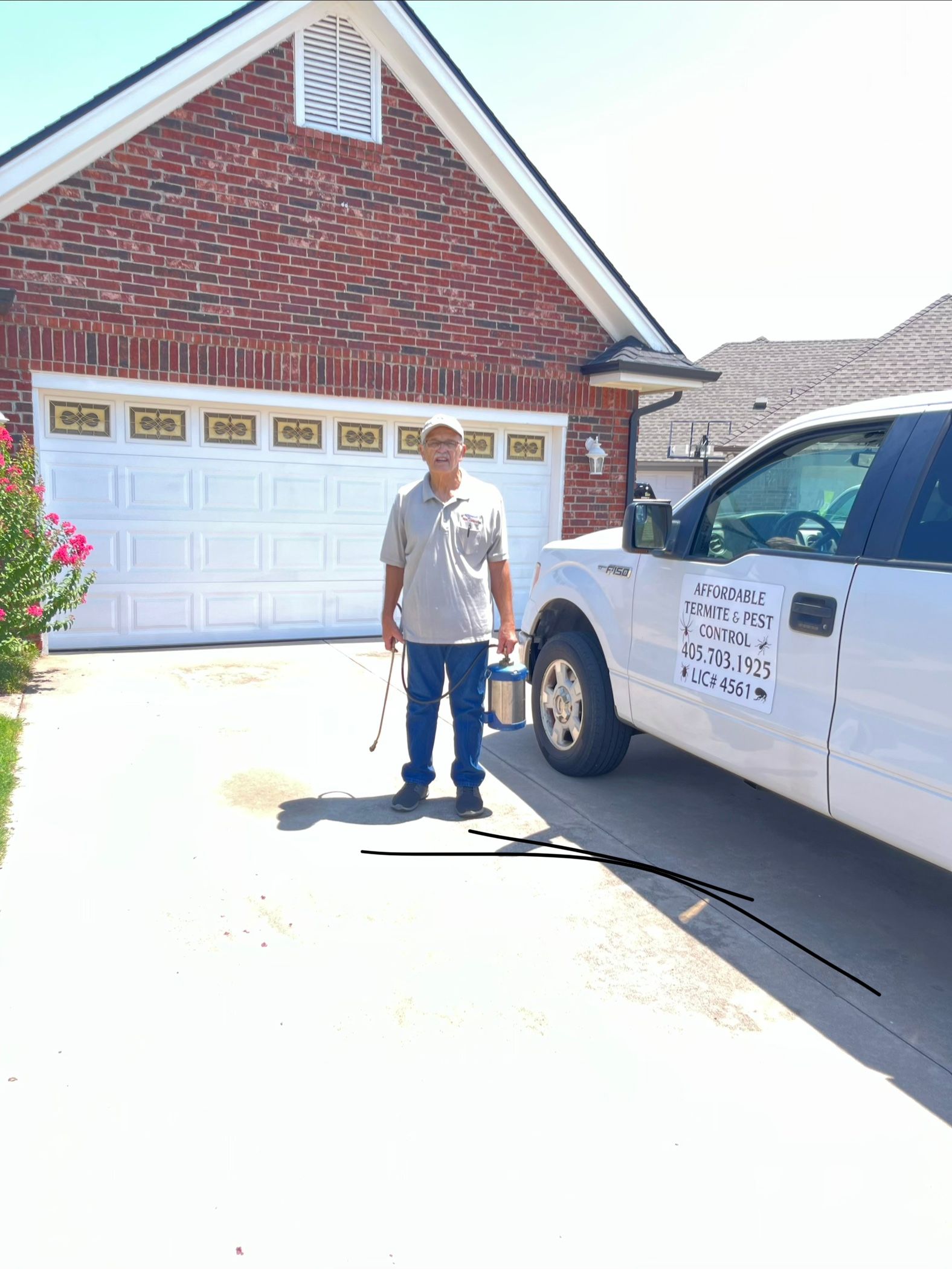 Person in protective suit spraying inside a kitchen cabinet.