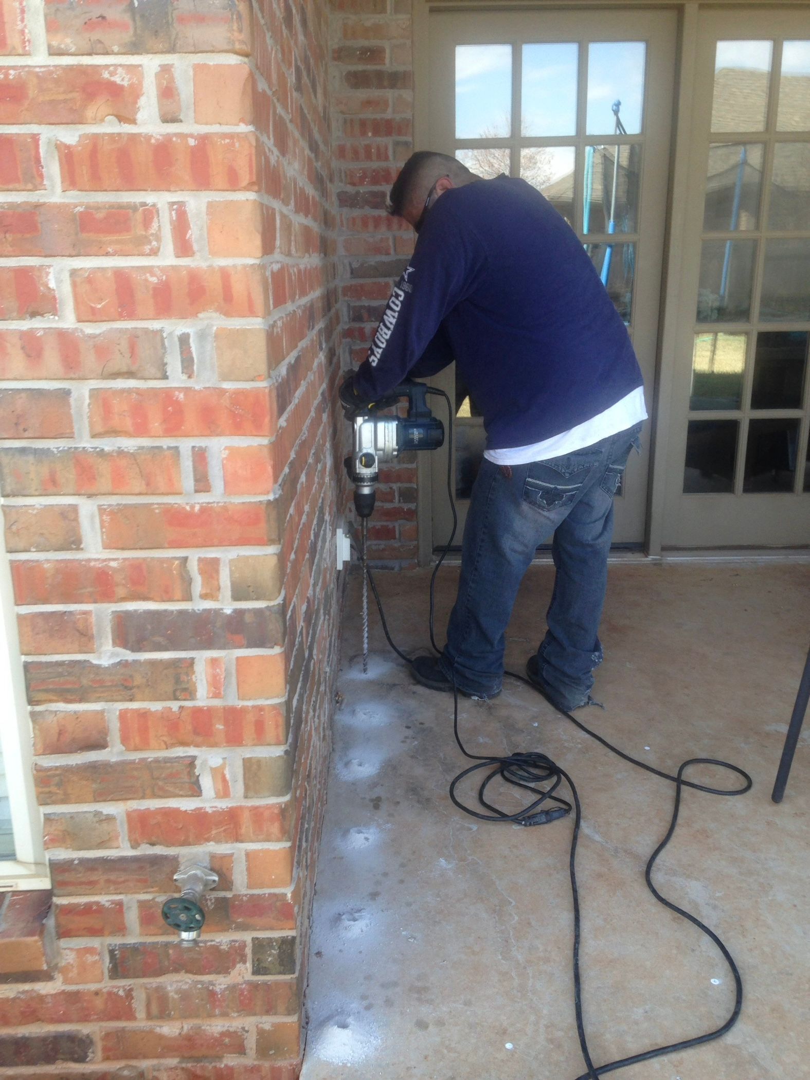 Person in protective suit spraying inside a kitchen cabinet.