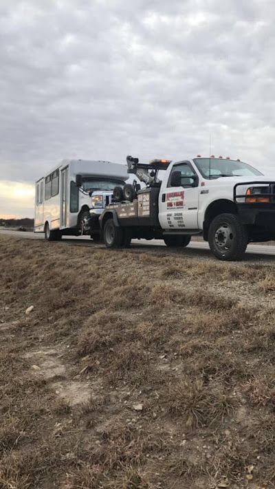 A tow truck is towing a trailer on the side of the road.