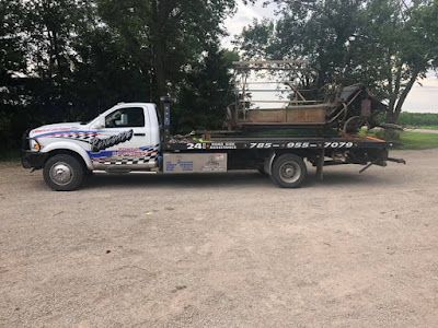 A tow truck is parked in a gravel lot.