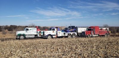 A group of tow trucks are parked in a field.