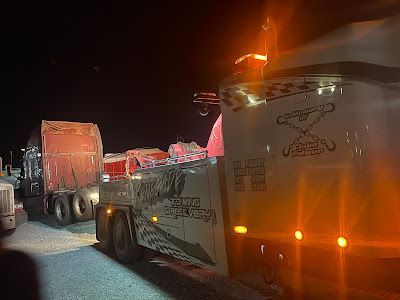 A tow truck is towing a trailer at night.