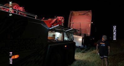 A man is standing in front of a truck at night.