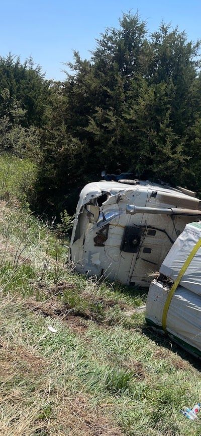 A camper is laying on its side in a grassy field.