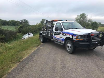 A tow truck is towing a car on the side of the road.