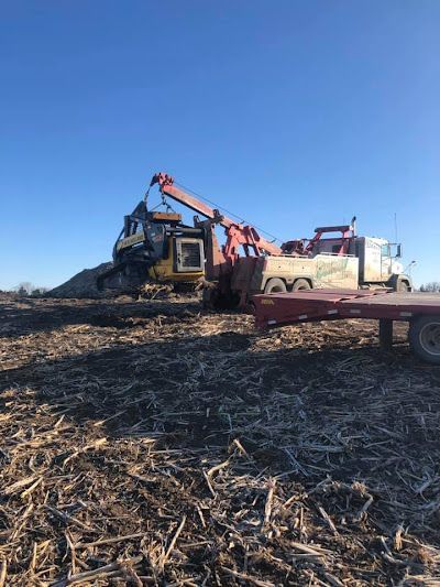 A tow truck is towing a bulldozer in a field.