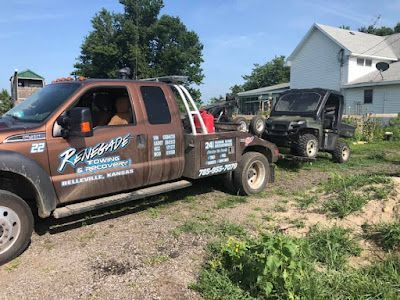 A tow truck is towing a vehicle in a field.