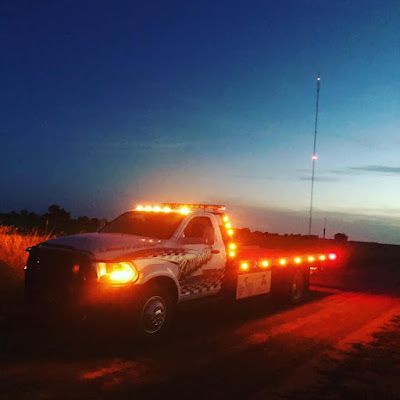 A tow truck is parked on the side of the road at night.