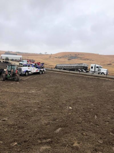 A truck is driving down a dirt road next to a tractor.