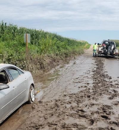 A car is stuck in the mud on a muddy road.