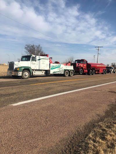 Two tow trucks are parked on the side of the road.