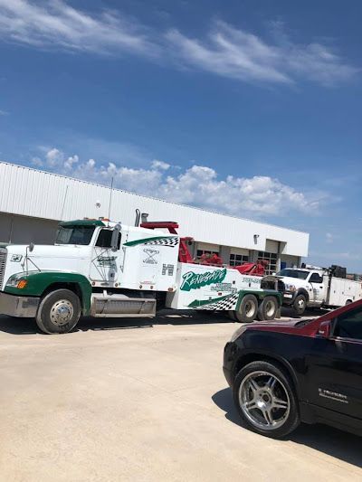 A tow truck is parked next to a car in front of a building.