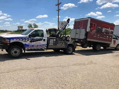 A tow truck is towing a box on a road.