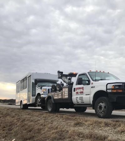 A tow truck is towing a trailer down a road.