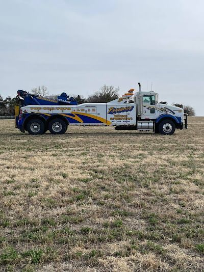 A white and blue tow truck is parked in a grassy field.