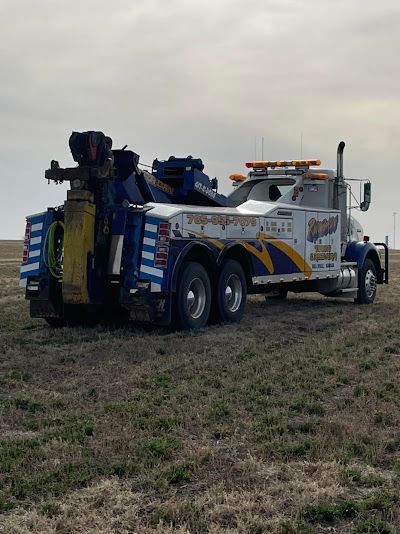 A blue and white tow truck is parked in a field.