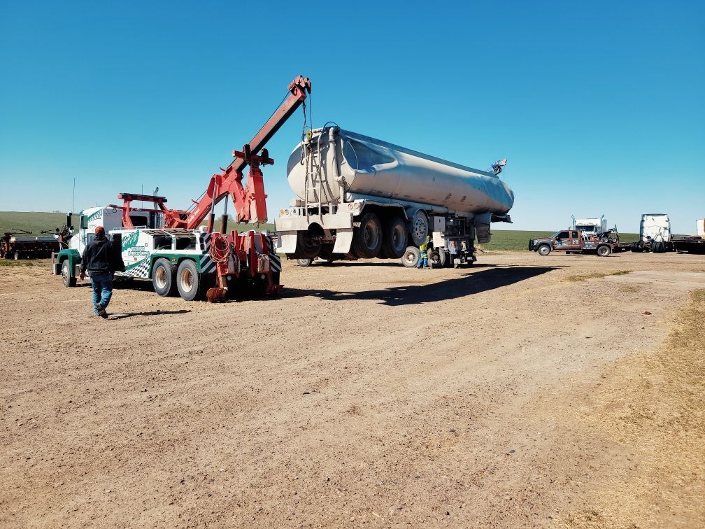A tanker truck is being towed by a tow truck