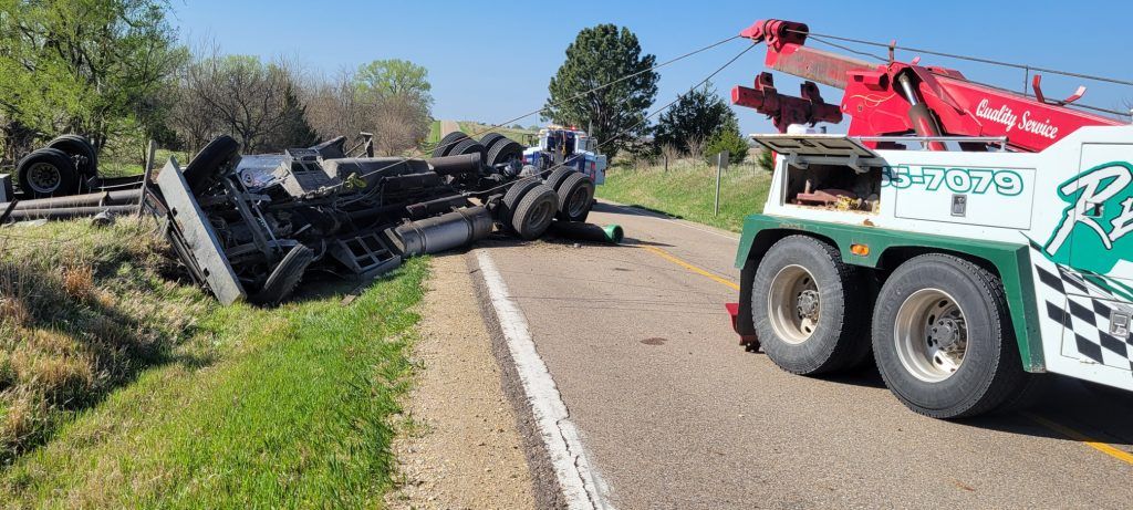 A tow truck is towing a truck that has fallen off the road.