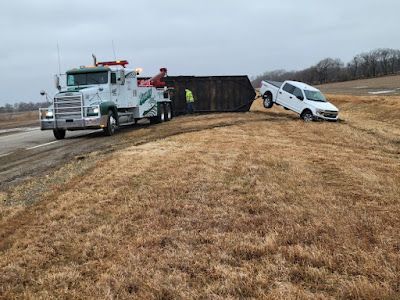 A tow truck is towing a truck that has fallen off the road.