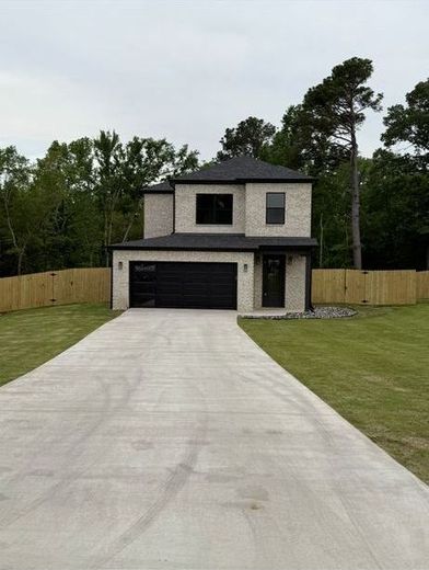 Two-story brick house with black accents, black garage door, and long concrete driveway.