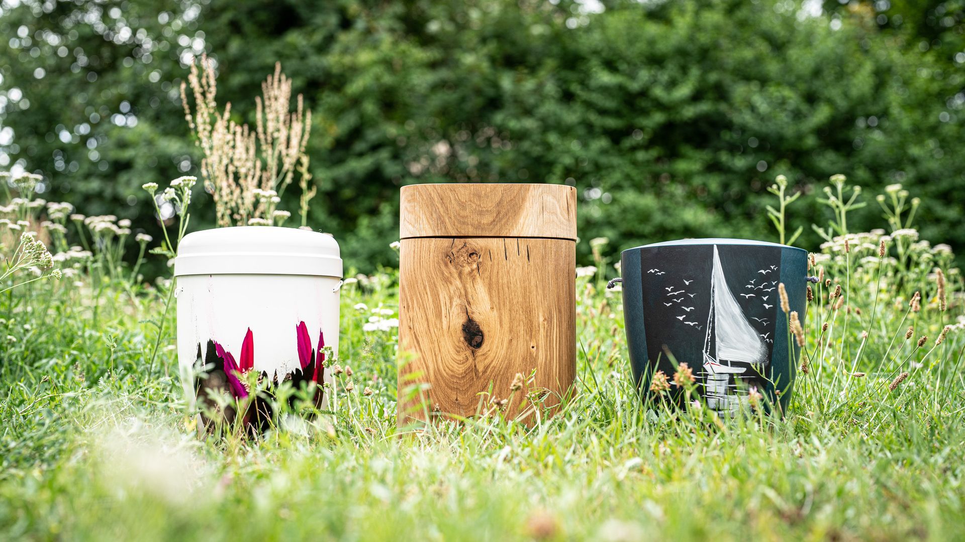 Drei Urnen stehen auf einem üppigen grünen Feld.