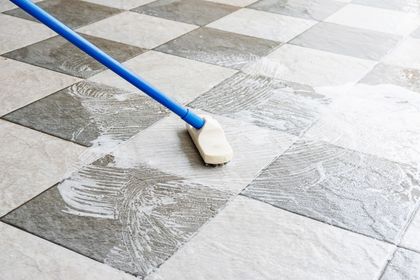 A person is cleaning a tiled floor with a mop.