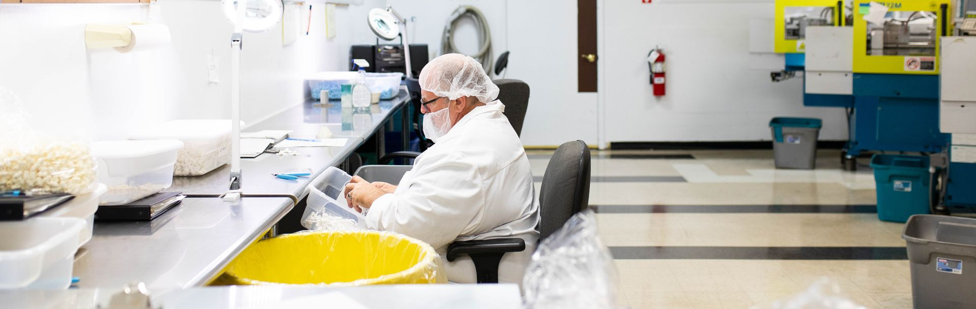 A state-of-the-art ISO-certified cleanroom with technician in protective gear working on medical devices under sterile conditions