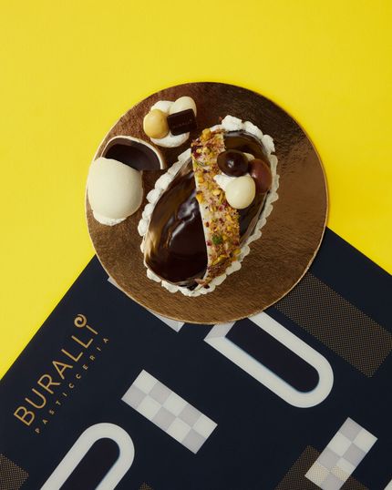 Un dessert al cioccolato è appoggiato sopra una pubblicità di Buralli