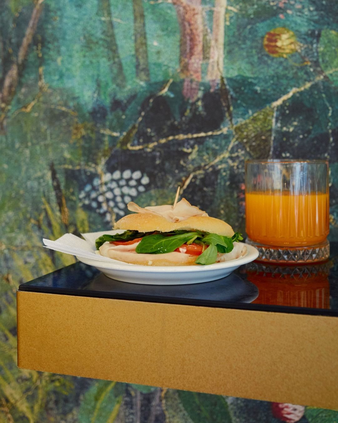 Un panino è su un piatto accanto a un bicchiere di succo d'arancia.