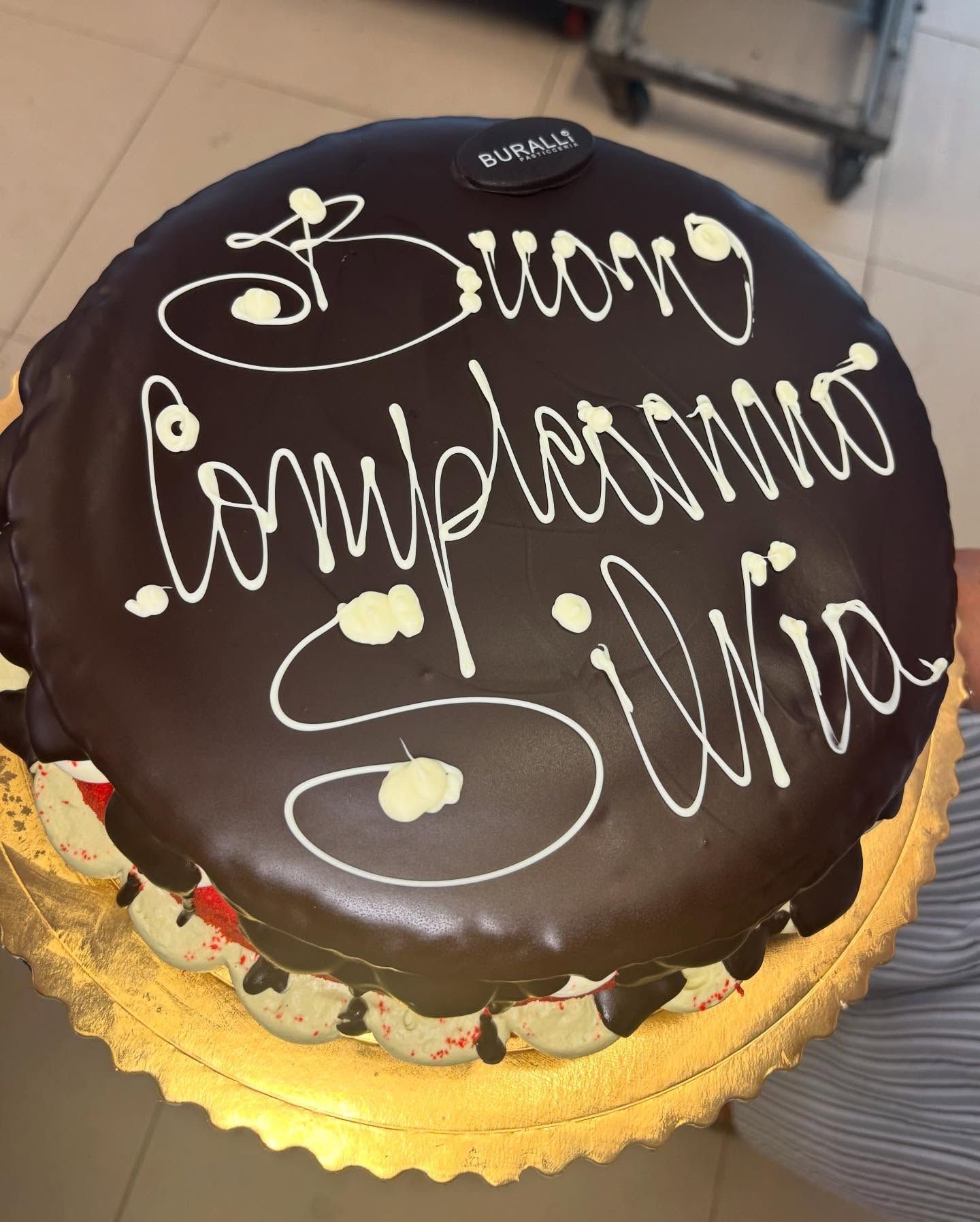 A chocolate cake that says buon compleanno silvia on it