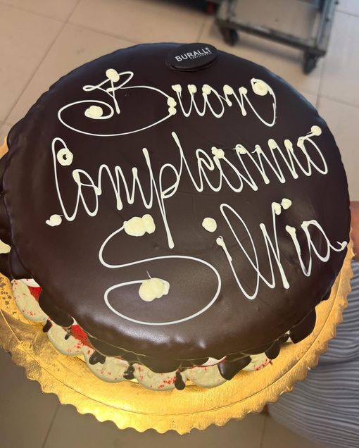 A chocolate cake that says buon compleanno silvia on it