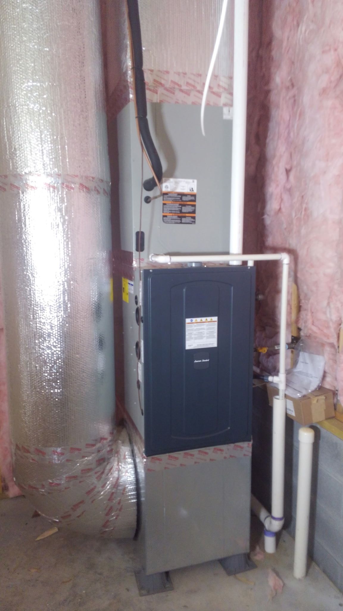 A water heater is sitting in a room next to a pipe.
