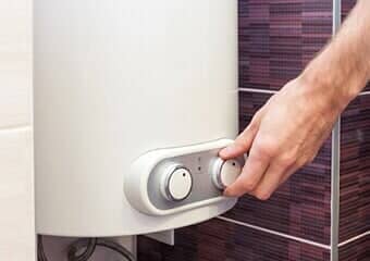Man hands setting the temperature of water in Electric Boiler — Boiler Installations in Central Valley, NY