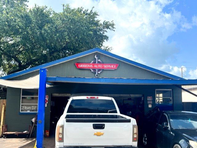 A white truck is parked in front of a garage.