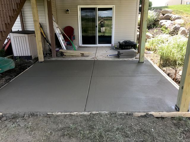 A concrete patio is being built in front of a house.