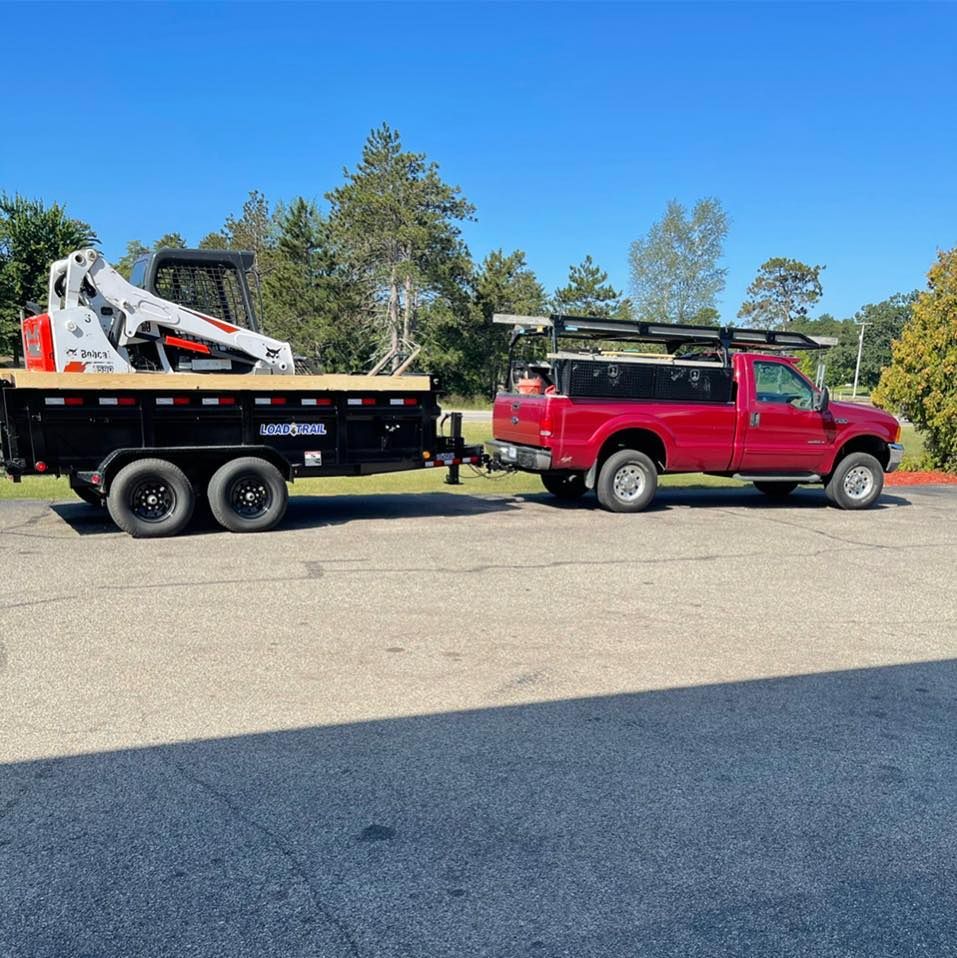 A red truck is towing a trailer with a bulldozer on it.