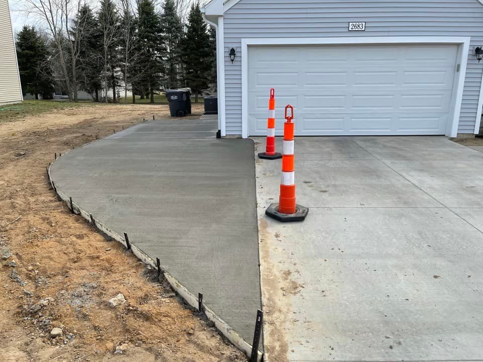 A concrete driveway is being built in front of a garage.