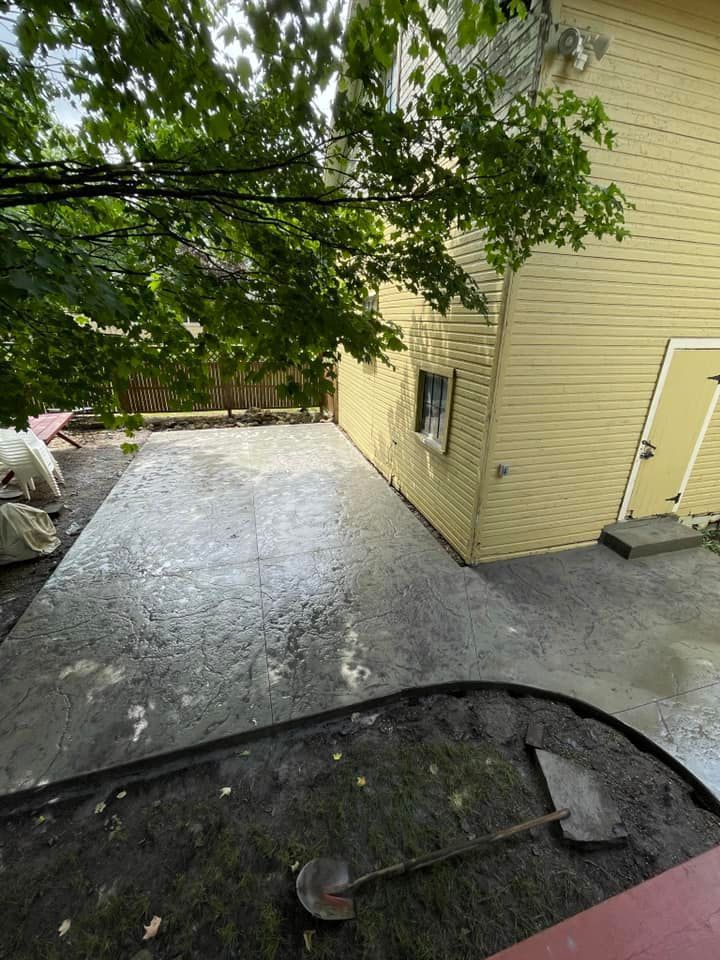 A concrete patio is being built in front of a yellow house.