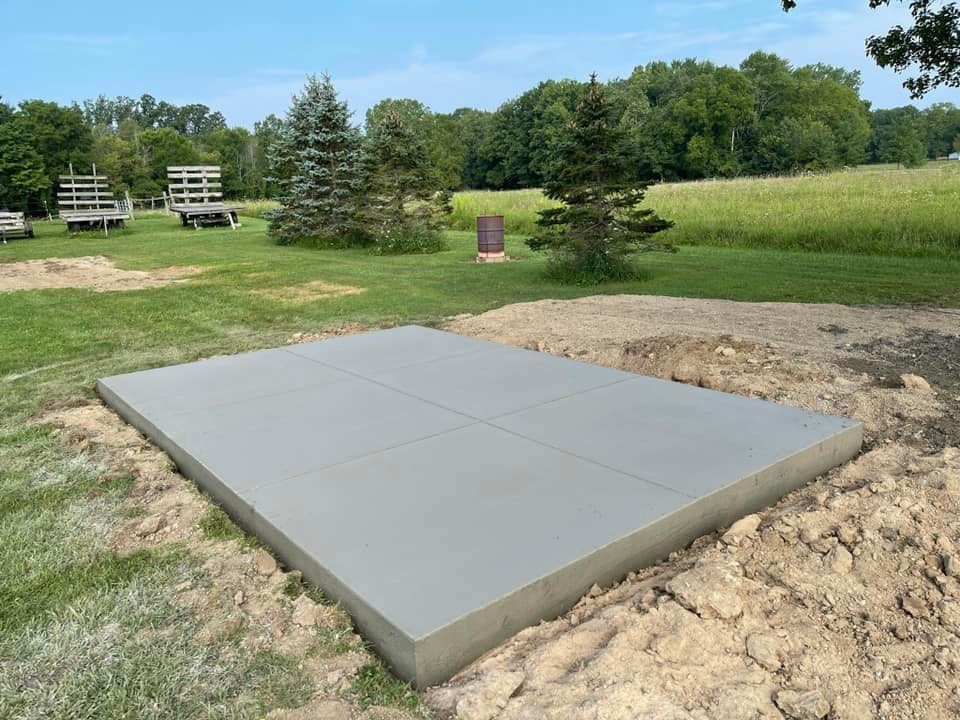 A large concrete slab is sitting in the middle of a grassy field.