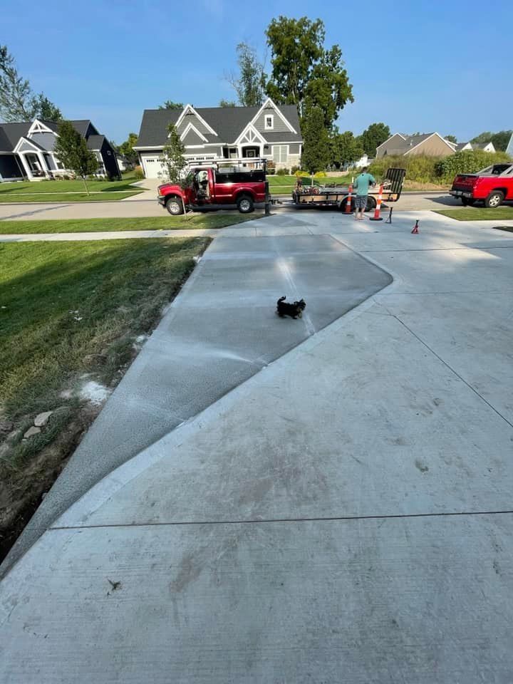 A red truck is parked on the side of a concrete driveway next to a house.