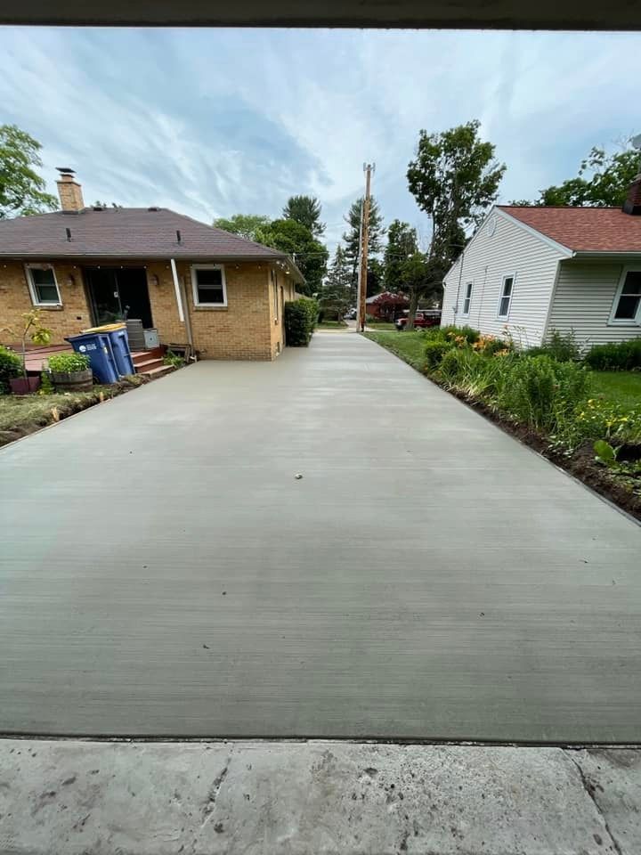 A concrete driveway leading to a brick house.