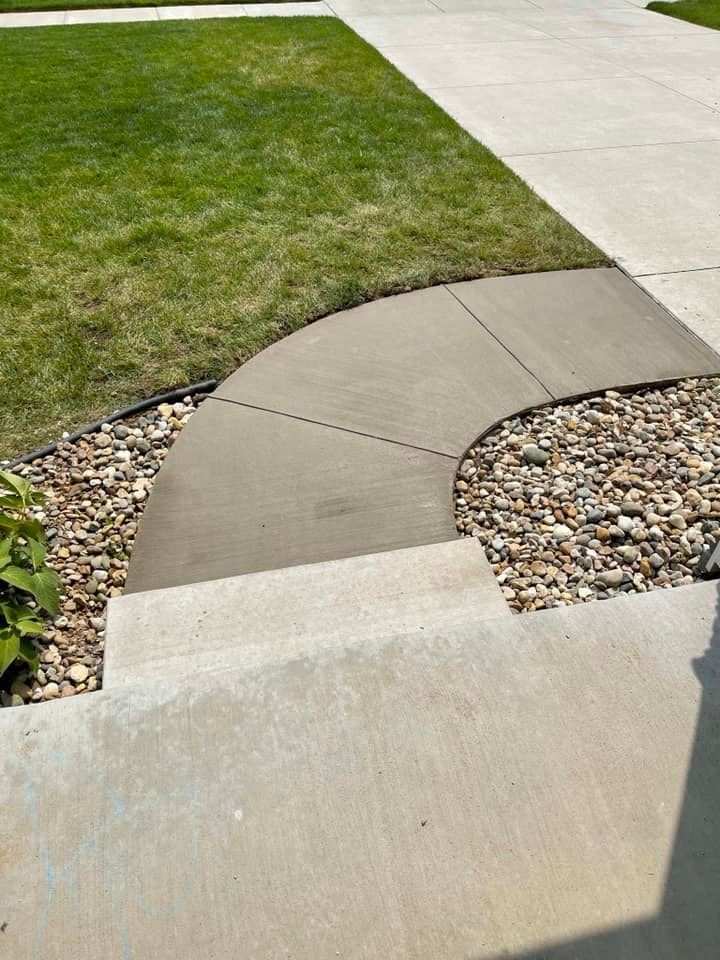 A concrete walkway with a grassy lawn in the background.