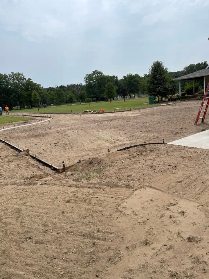 A dirt field with a house in the background and a ladder in the foreground.