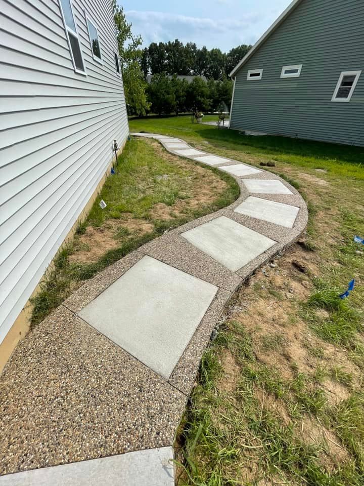 A concrete walkway leading to a house in the backyard.