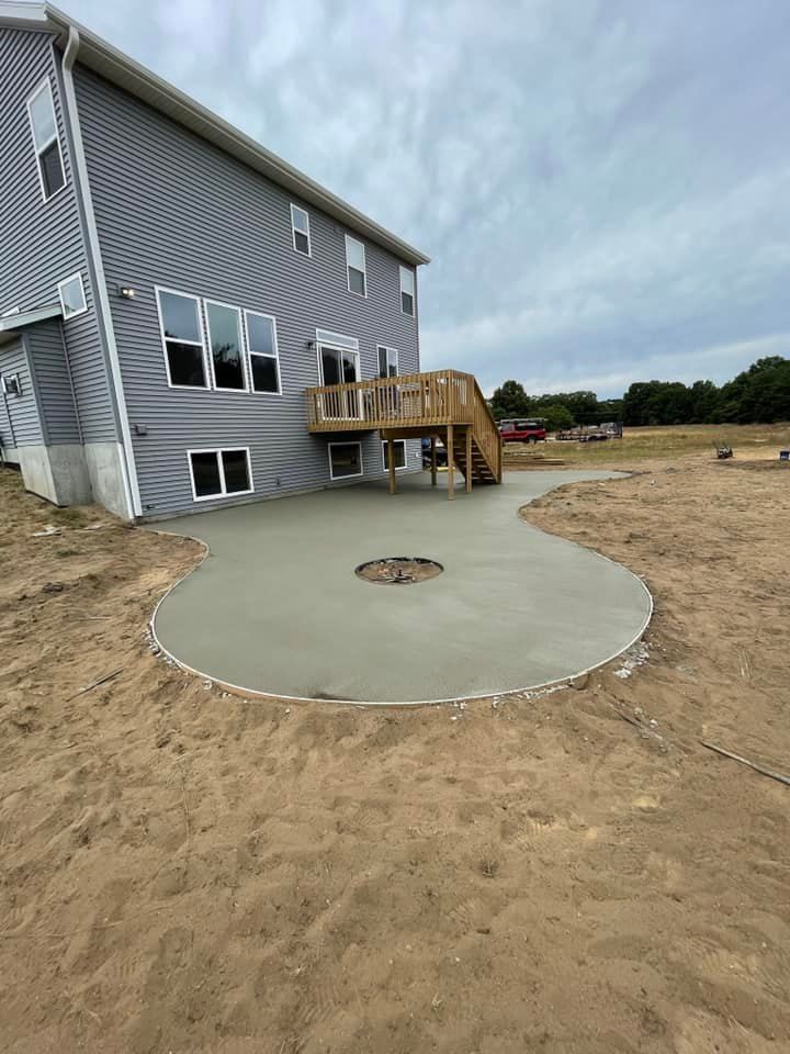 A large house with a concrete patio and a wooden deck.