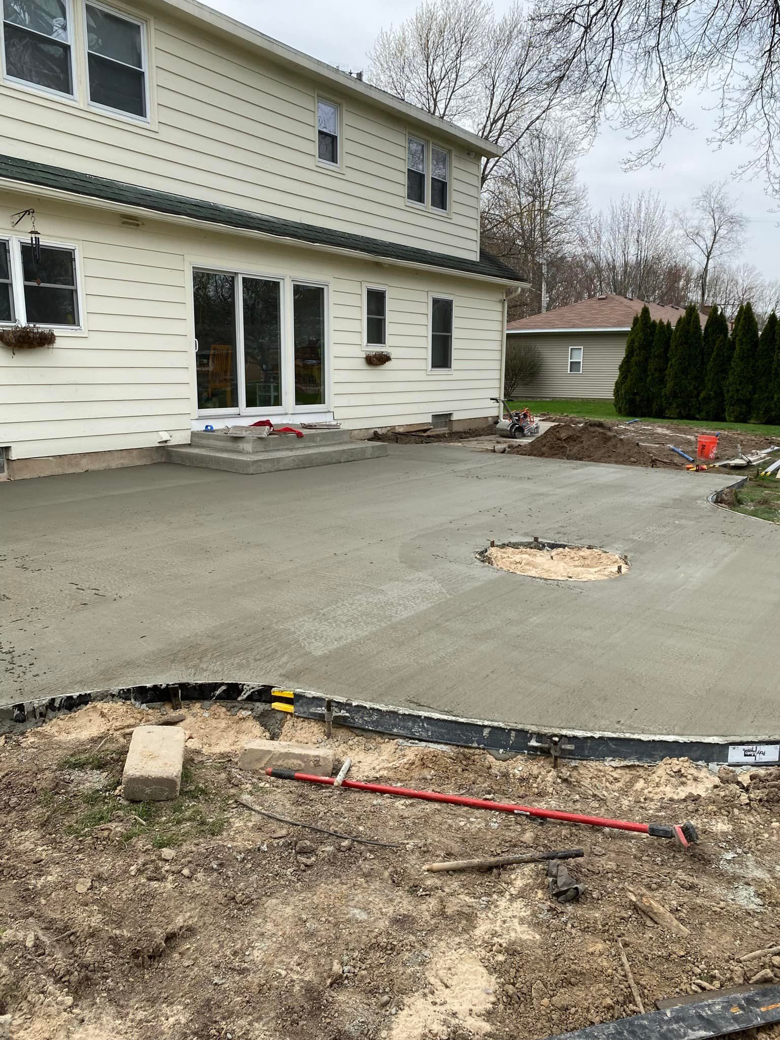 A concrete patio is being built in front of a house.