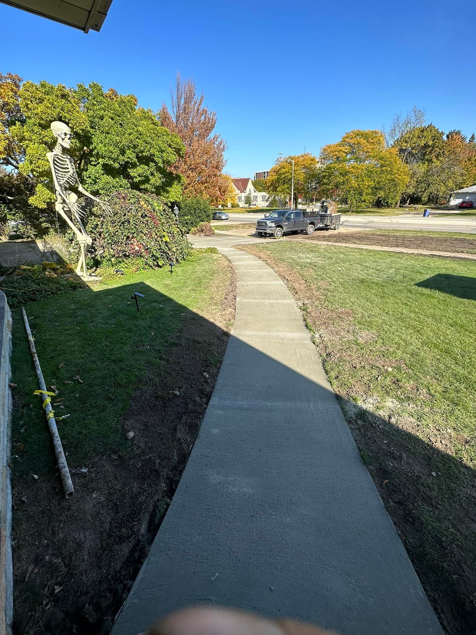 A skeleton is standing on the sidewalk in front of a house.
