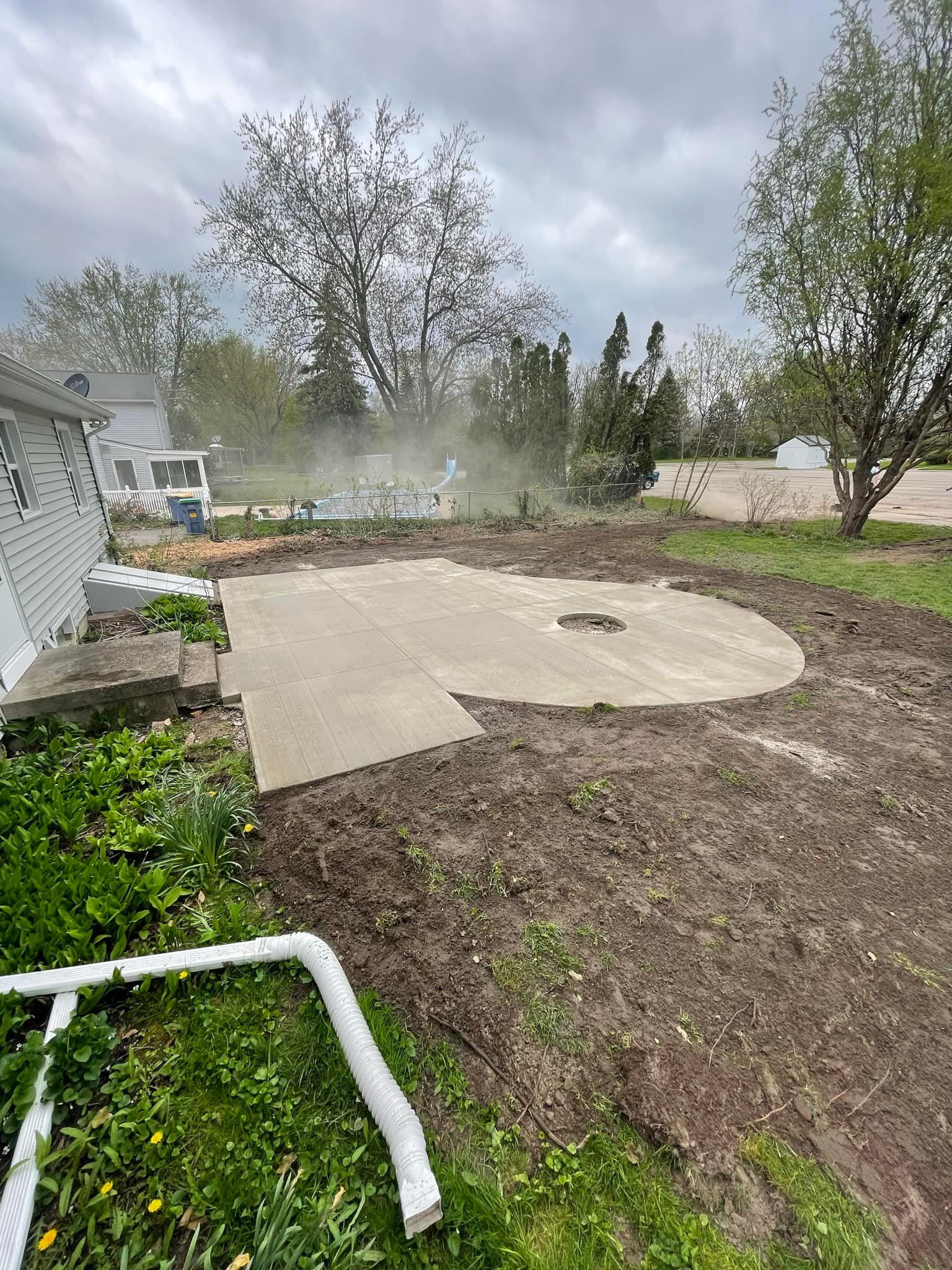 A concrete patio is being built in the backyard of a house.
