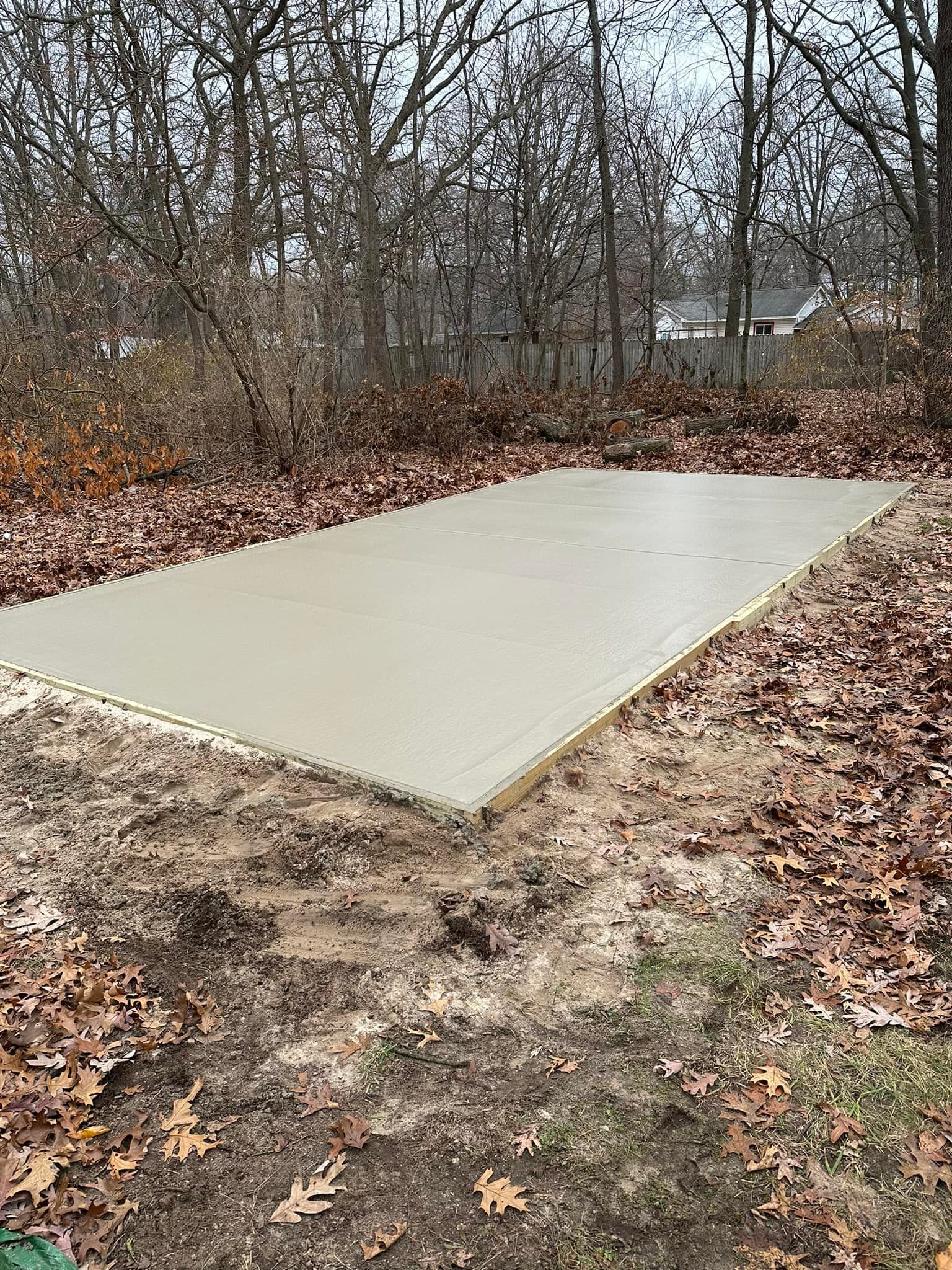 A large concrete slab is sitting in the middle of a dirt field surrounded by trees.